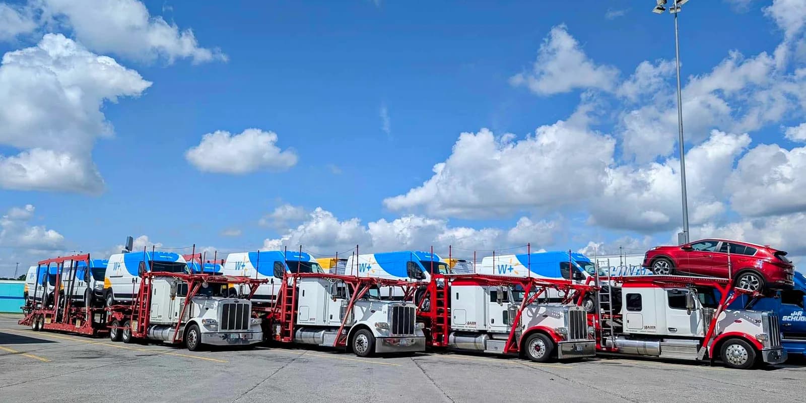 Car shipping cost guide 2026 — Baier Transport multi-car carriers loaded at a logistics yard under bright daylight