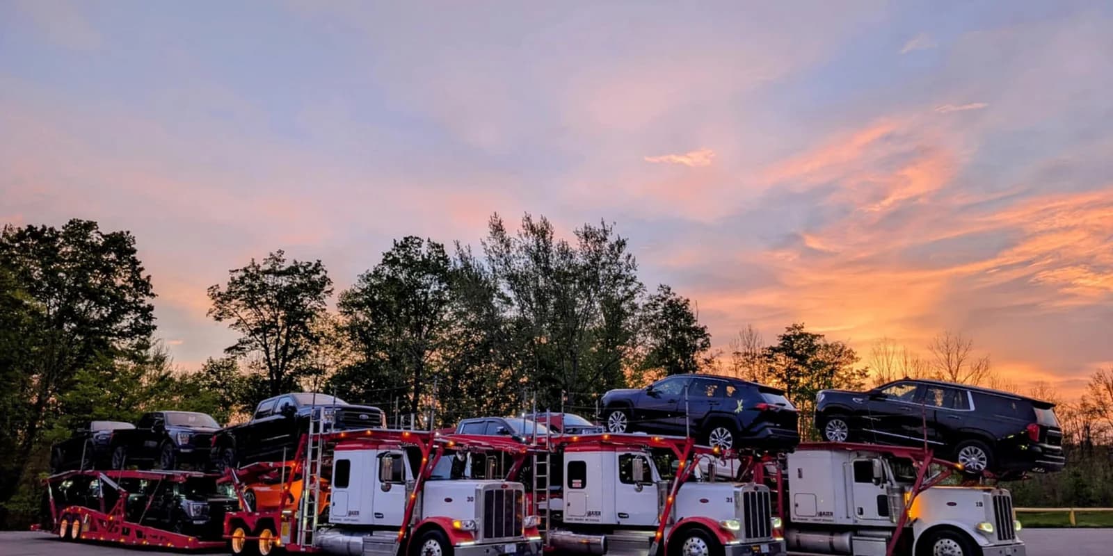 Snowbird auto transport guide — three Baier Transport rigs lined up at sunset preparing for a seasonal route