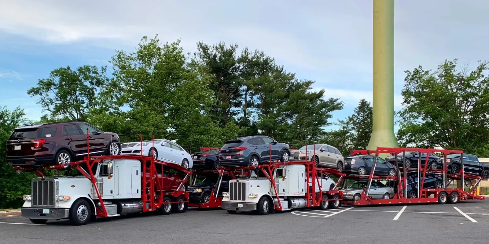 Two Baier Transport Peterbilt car carriers fully loaded in a parking lot