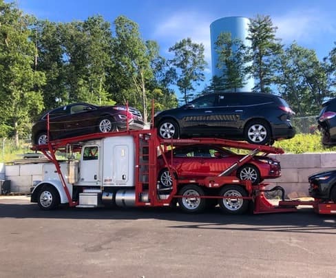 Multi-car carrier loaded with SUVs at the Baier Transport facility in summer